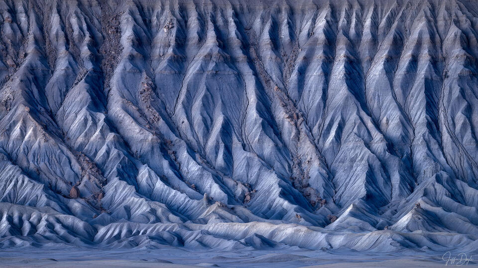 Close-up telephoto view of Factory Butte's eroded blue-grey clay ridges and channels in the Utah desert badlands
