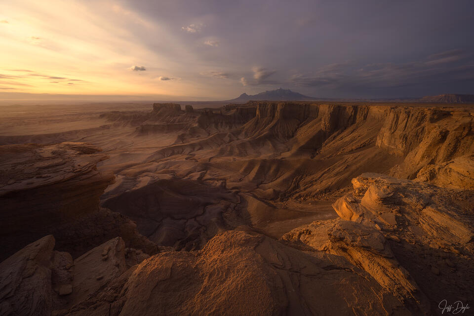 Sweeping canyon badlands at sunrise from Moonscape Overlook with storm clouds and Henry Mountains on the horizon