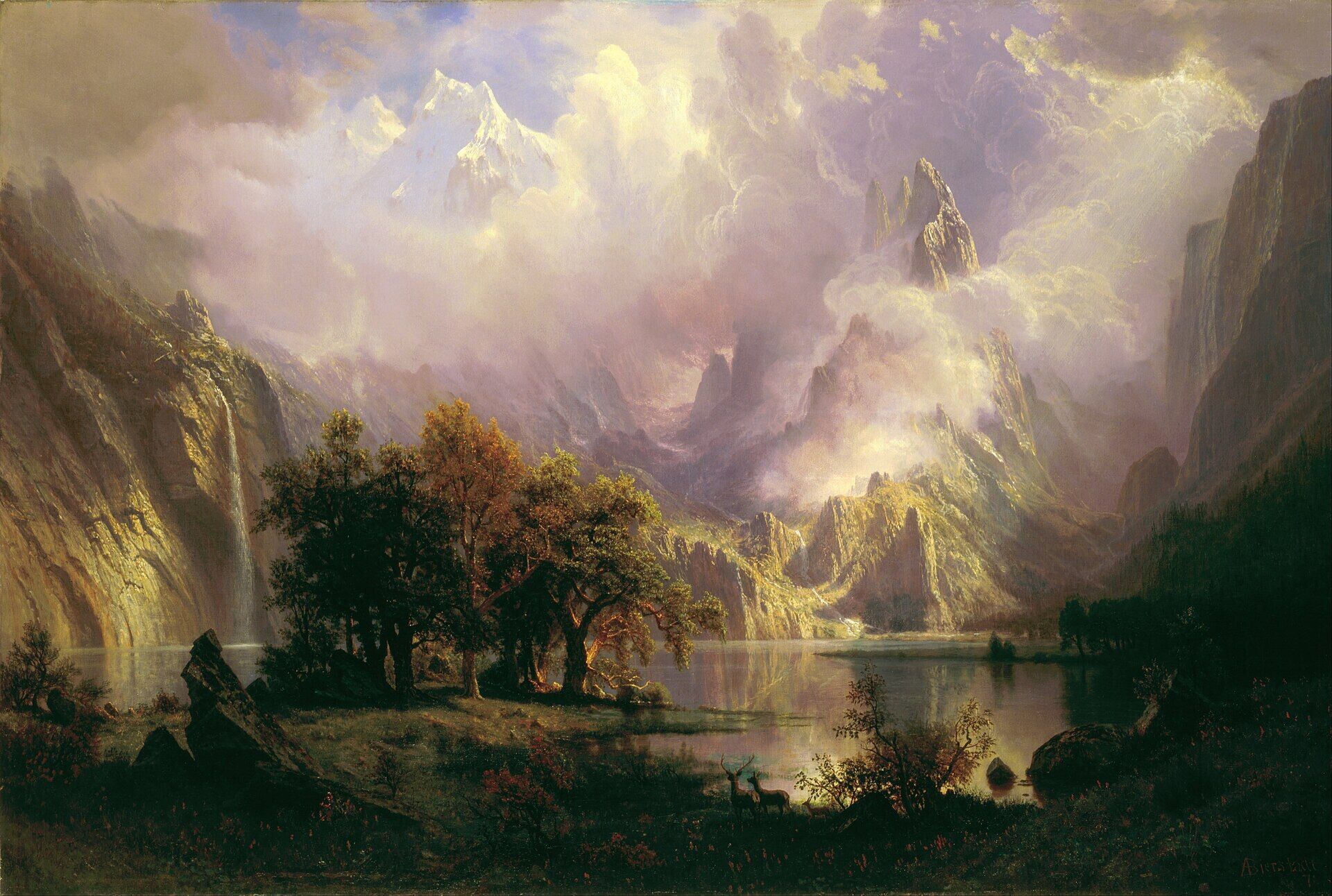 Albert Bierstadt painting of a luminous Rocky Mountain landscape, with misty peaks, dramatic clouds, waterfalls, a calm lake, autumn trees, and deer in the foreground.
