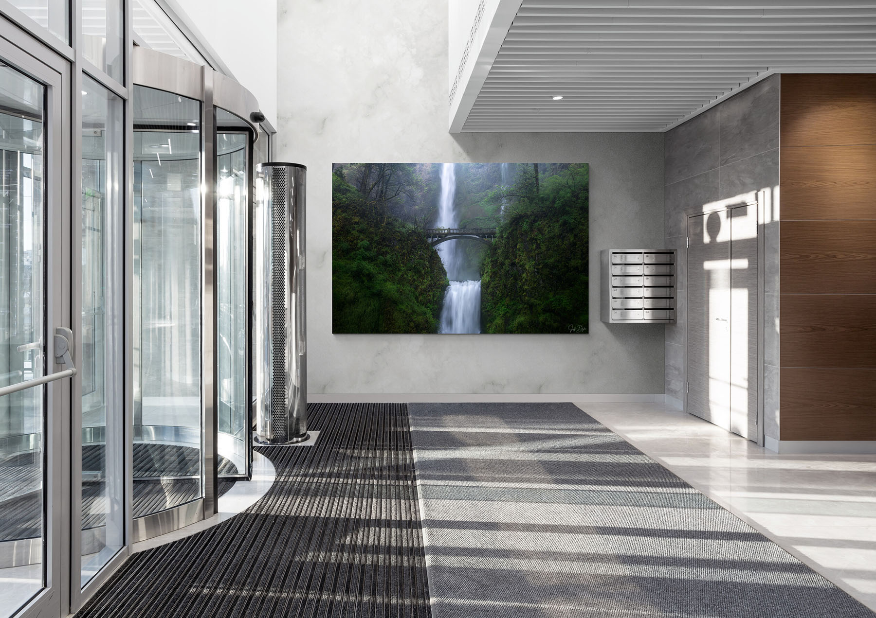 Modern corporate lobby interior with a large fine art waterfall print of Multnomah Falls in the Columbia River Gorge, Oregon displayed as a statement piece on a concrete feature wall.
