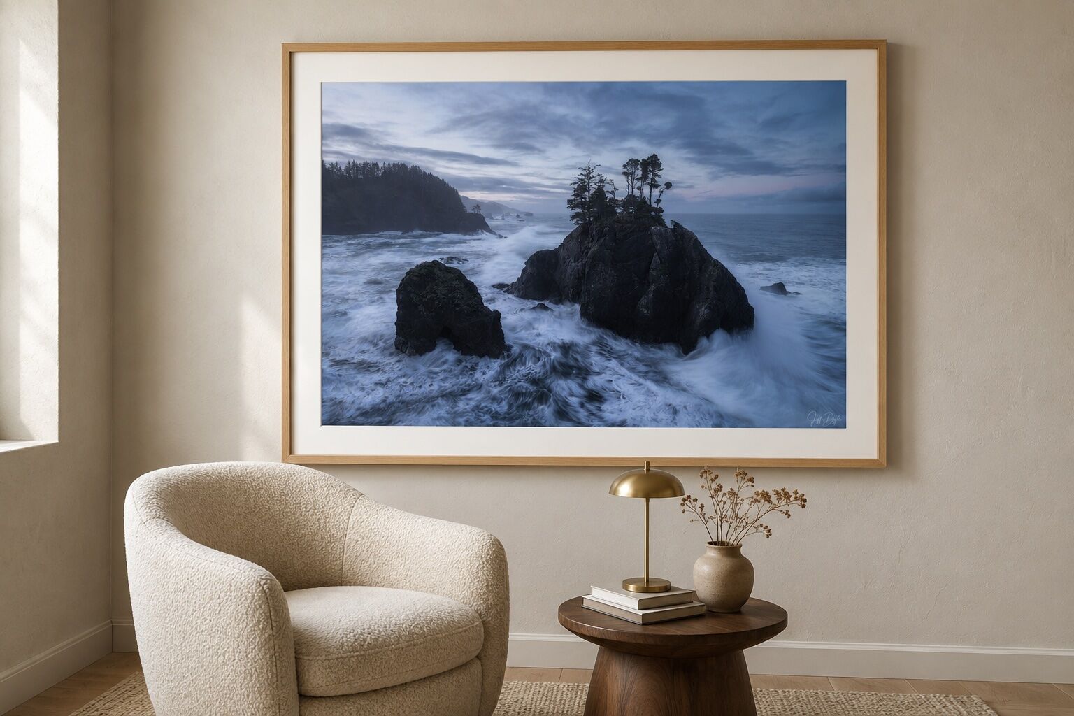 Framed Oregon coastal landscape print displayed above a bouclé chair in a warm neutral residential sitting area.