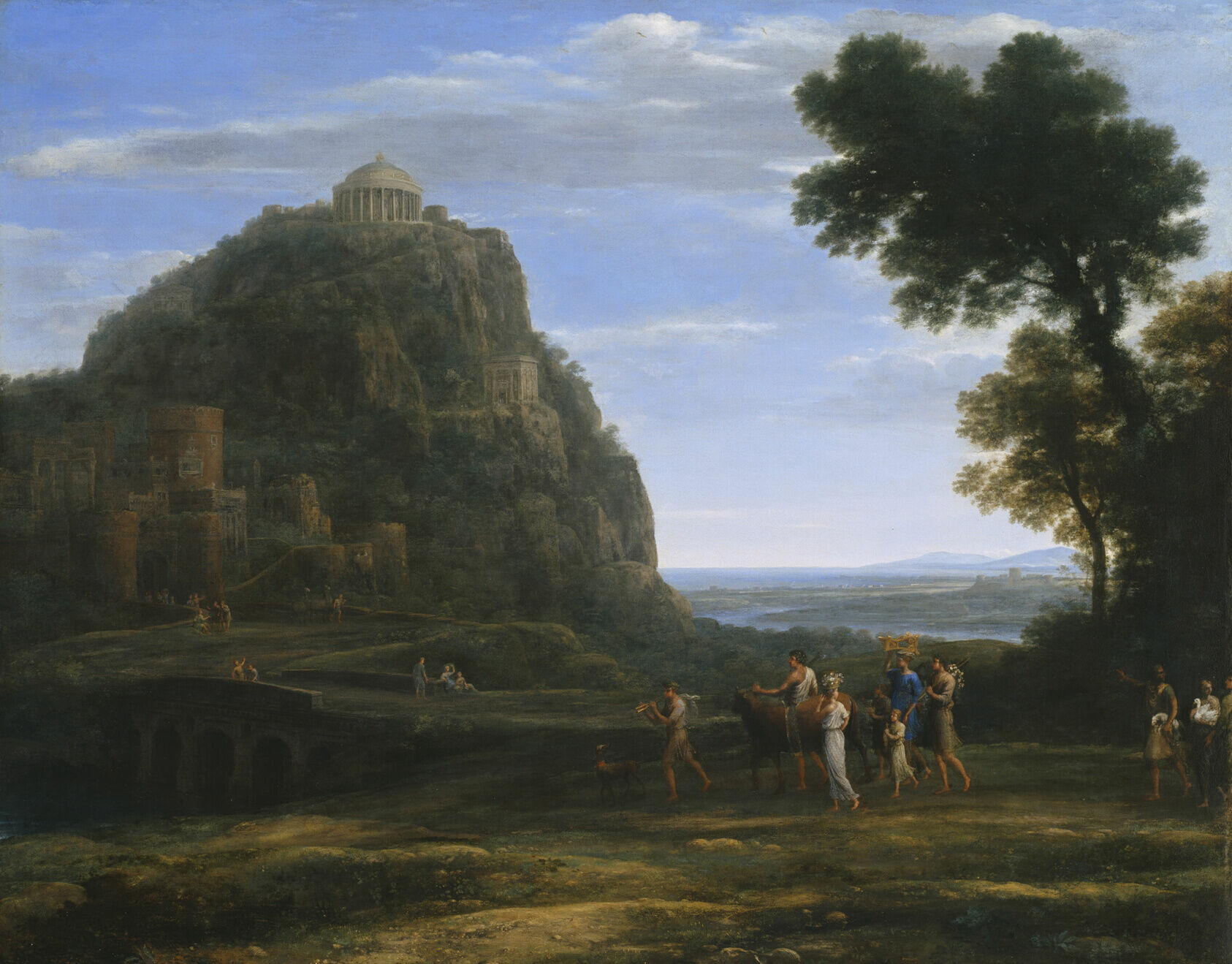 Classical landscape painting depicting an ancient temple atop a rocky hill overlooking a wide valley and distant sea. In the foreground, small groups of figures walk through a pastoral landscape with trees and ruins, while soft light and expansive sky create a serene, idealized view inspired by the ancient site of Delphi.